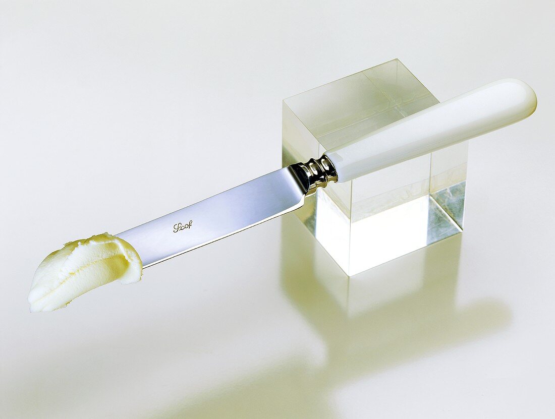 Ein Stück Butter auf einem Messer mit weißem Griff