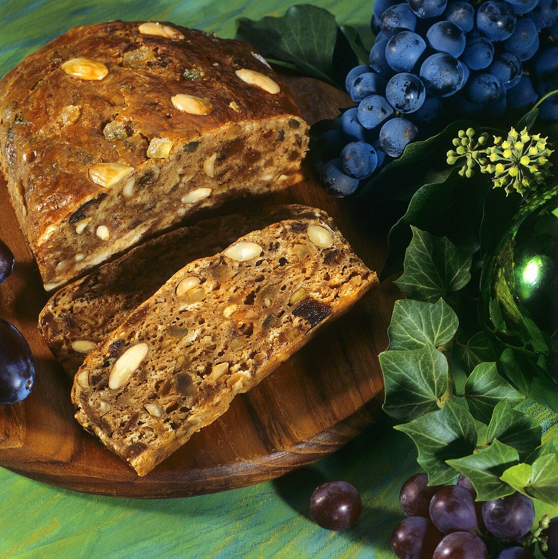 Fruit loaf on wooden plate and red and black grapes