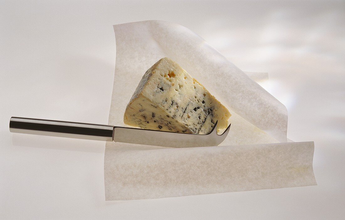 Ein dreieckiges Stück Österzola-Käse mit Käsemesser