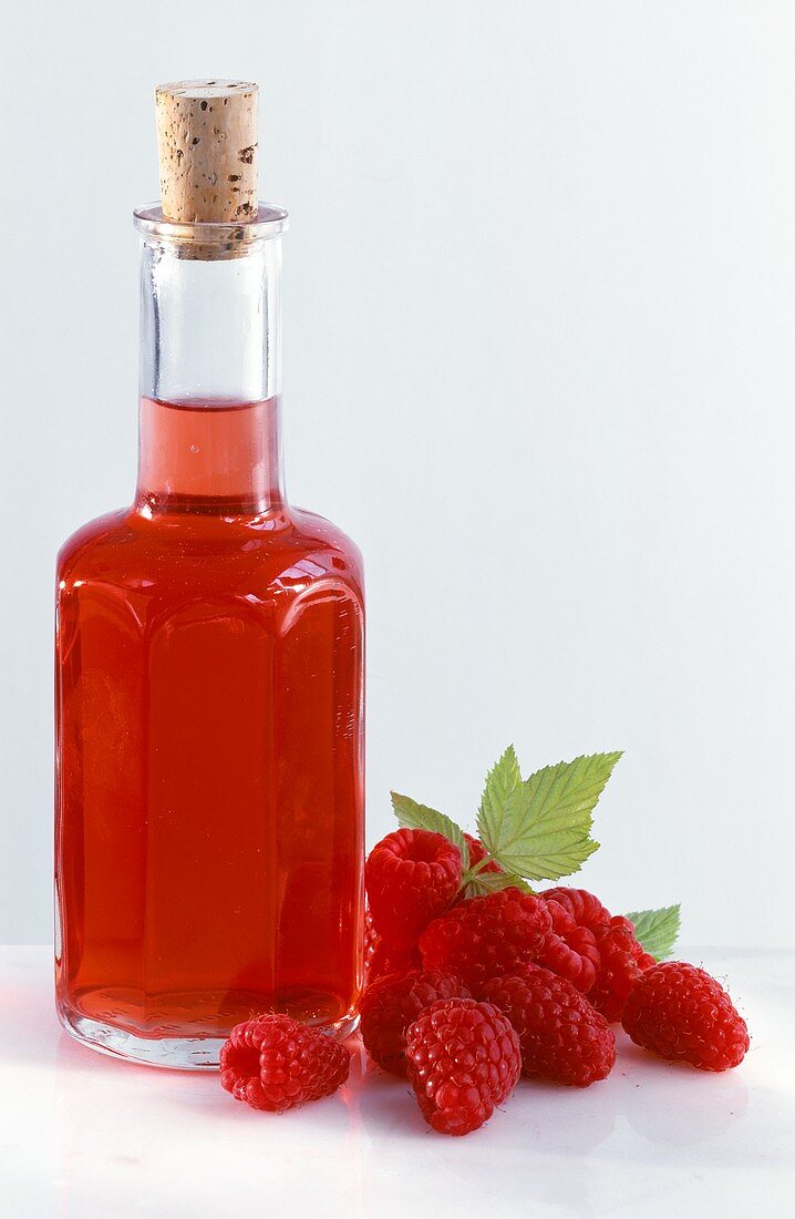 A bottle of raspberry vinegar, a few fresh raspberries 