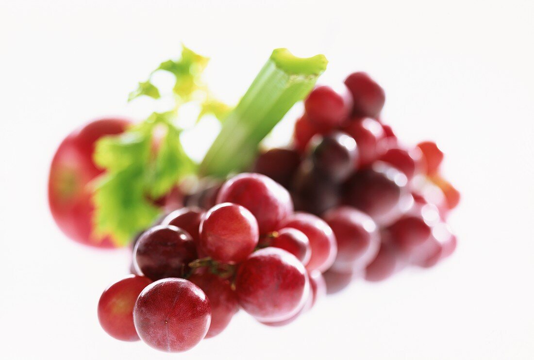 Red grapes, celery and apple on white background