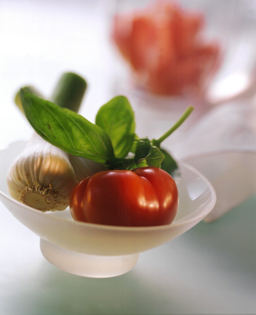 Tomato, fresh garlic and basil in white bowl