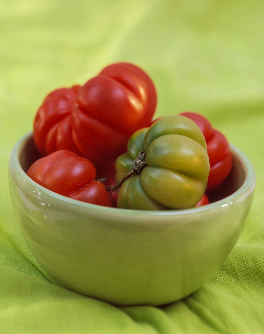 Einige reife Tomaten & eine grüne Tomate in hellgrüner Schale