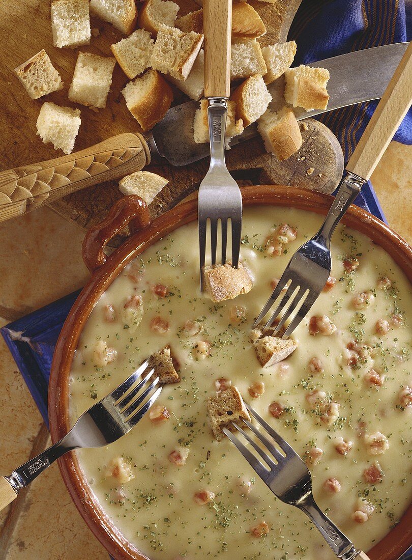 Hearty cheese & bacon fondue in caquelon with bread on forks