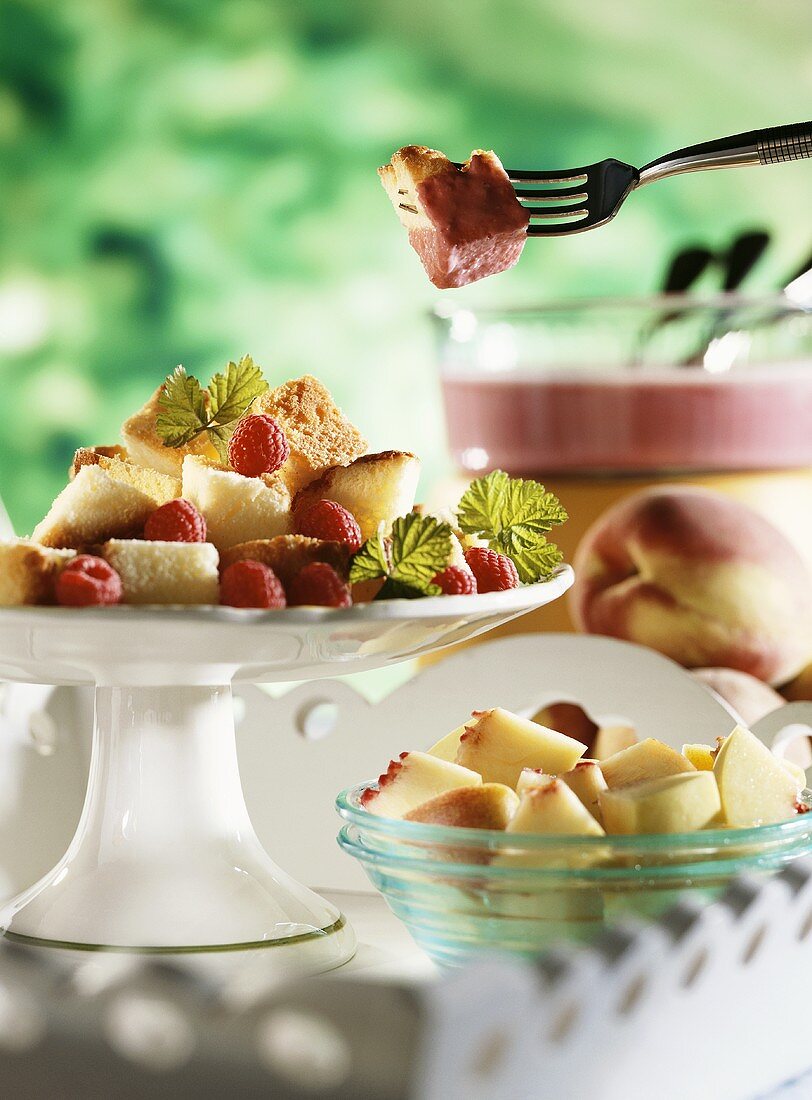Raspberry fondue with pieces of peach and Madeira cake