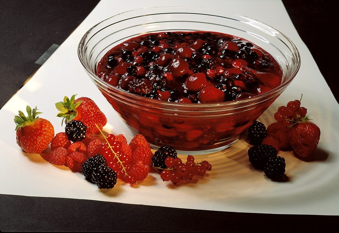 Red berry cream in glass bowl, with fresh berries in front