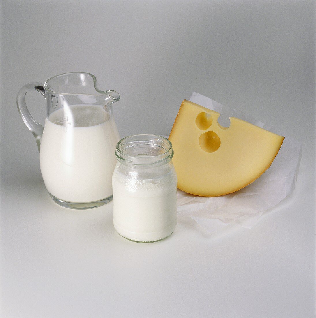 Cream in glass jug, yoghurt in glass & a piece of cheese