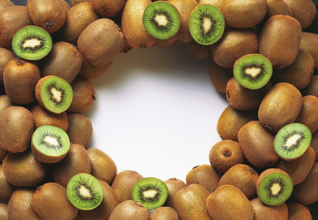 Whole and halved kiwi fruits, grouped around picture edge