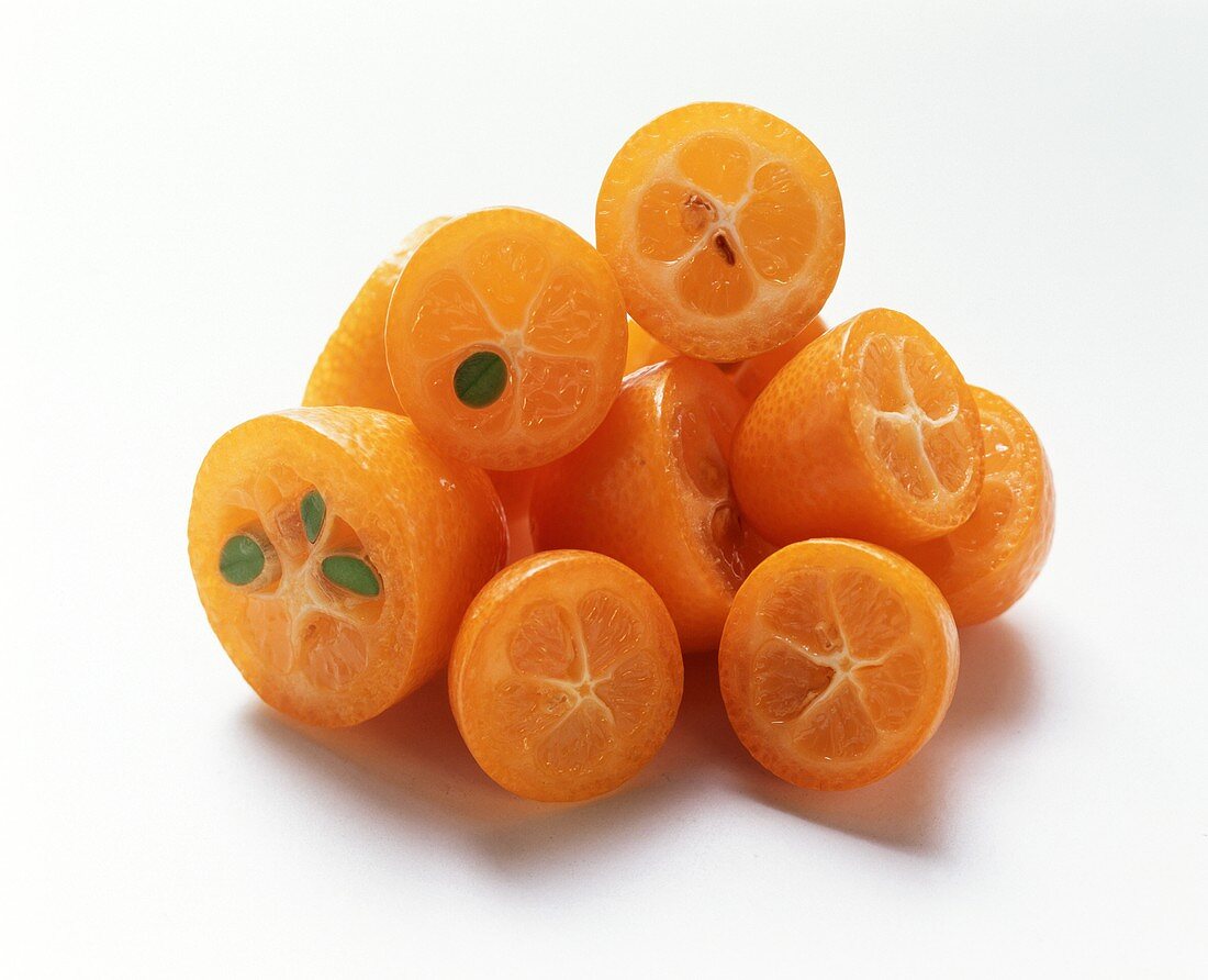 Mehrere halbierte Kumquats mit Kernen auf weißem Untergrund