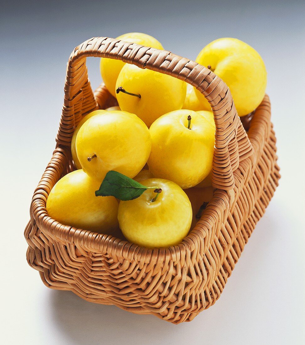 Several yellow plums in a basket