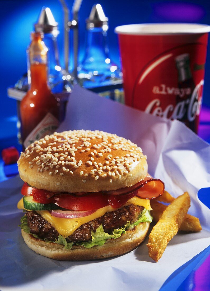 Cheeseburger mit Speck und zwei Pommes frites auf Papier