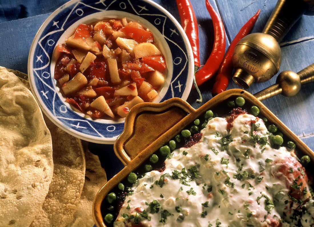 Indian baked potatoes with yoghurt sauce, peas & chutney