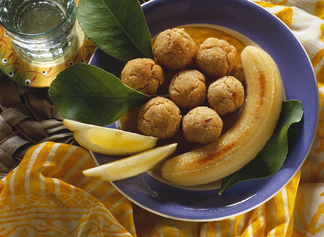 Bean balls with fried bananas and lemon wedges