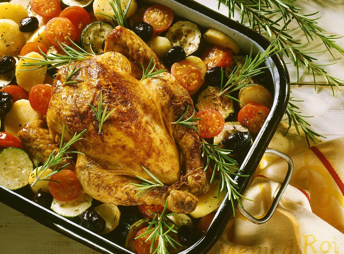 Rosemary chicken on a bed tomatoes, olives, potatoes