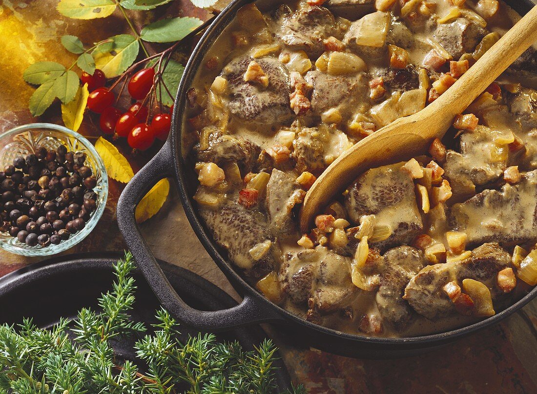 Wild boar ragout in the pot with a wooden spoon