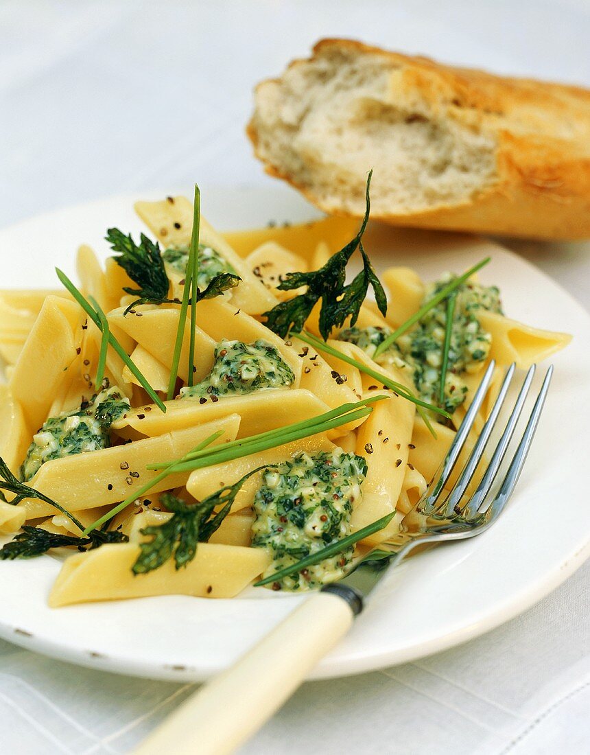 Penne with herb & cheese sauce on plate, décor: baguette