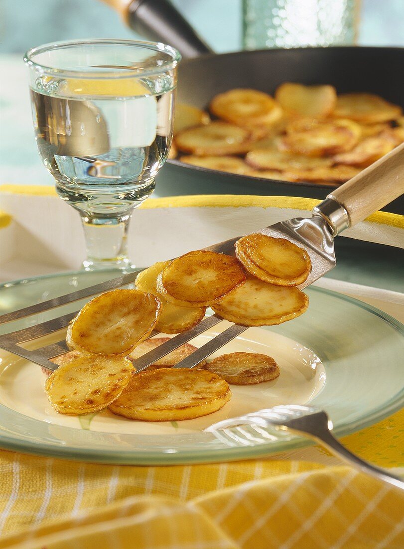 Fried sliced potatoes on plate and spatula