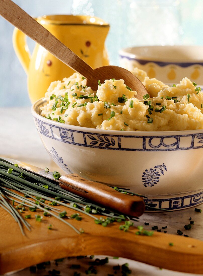 Mashed potato with chives in dish with wooden spoon