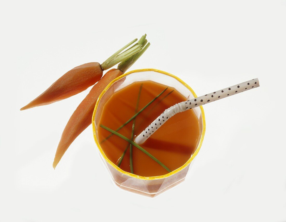Carrot juice with chives in glass, two carrots beside it