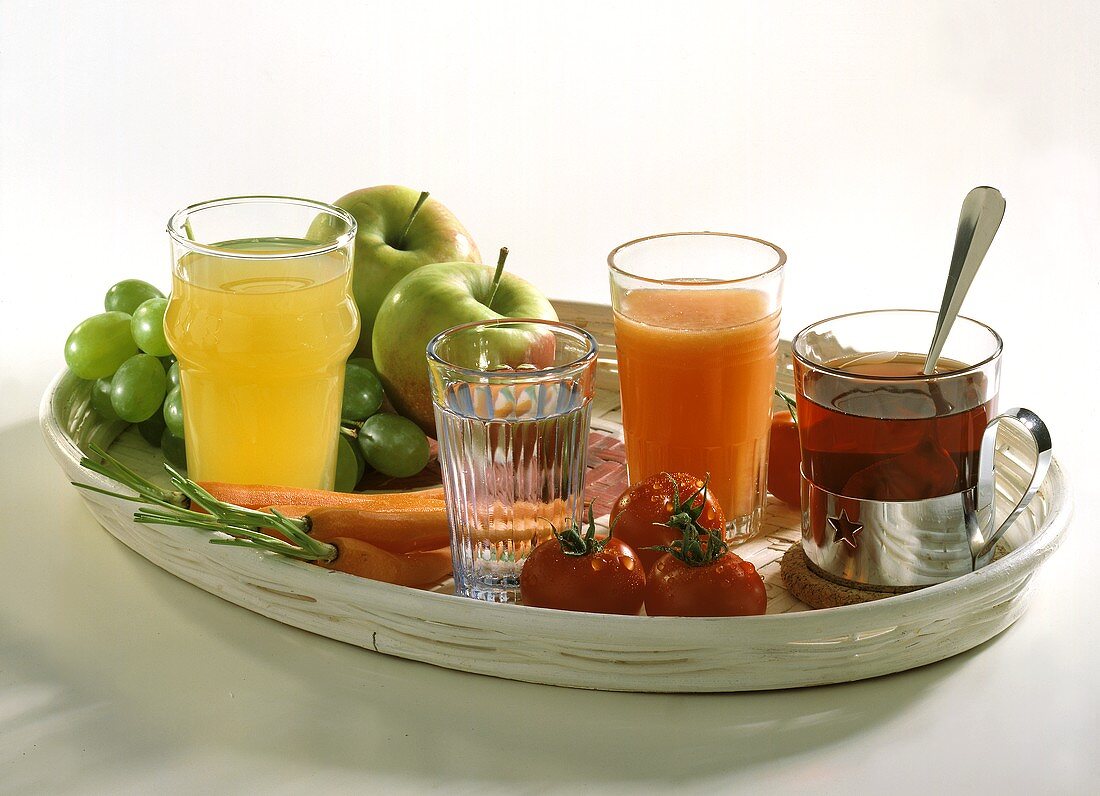 Various juices & tea in glass with fruit, vegetables on tray