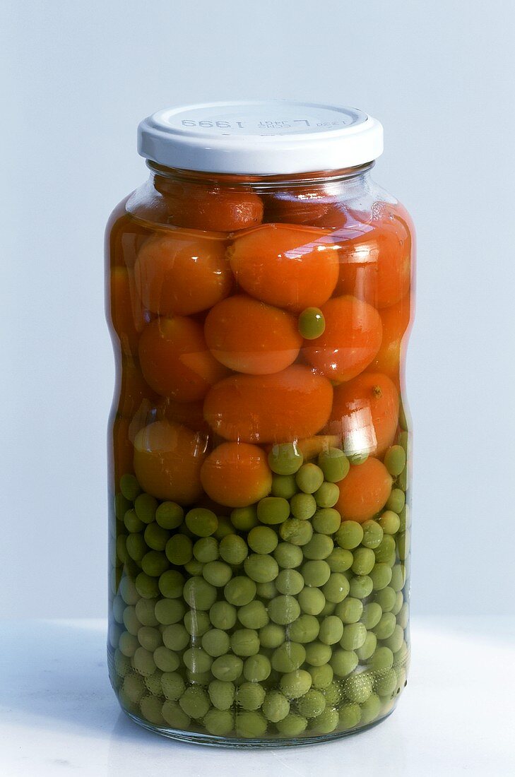 Carrots and peas in jar on light background
