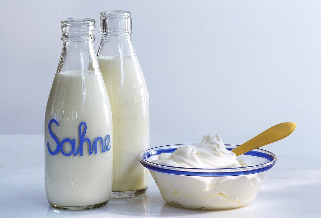 Two bottles of cream & whipped cream in blue-rimmed bowl