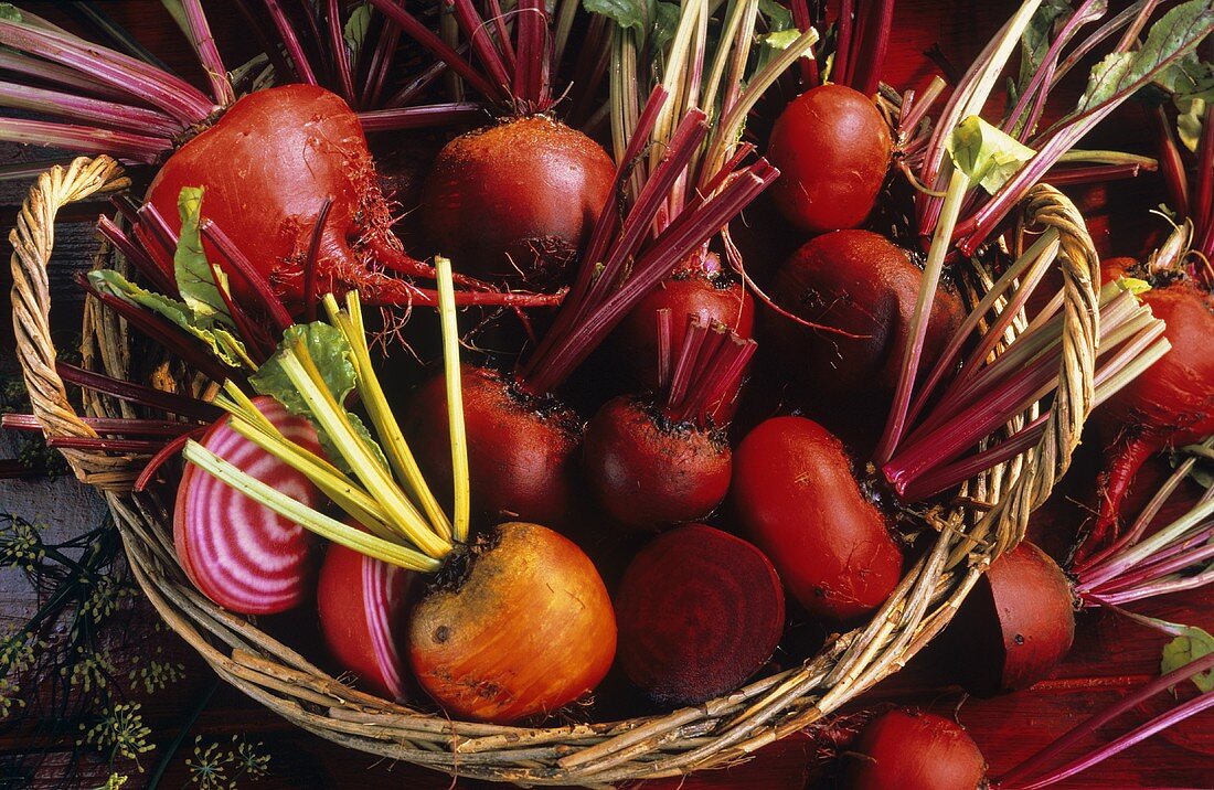 Many beetroots with leaves, whole & halved, in a basket