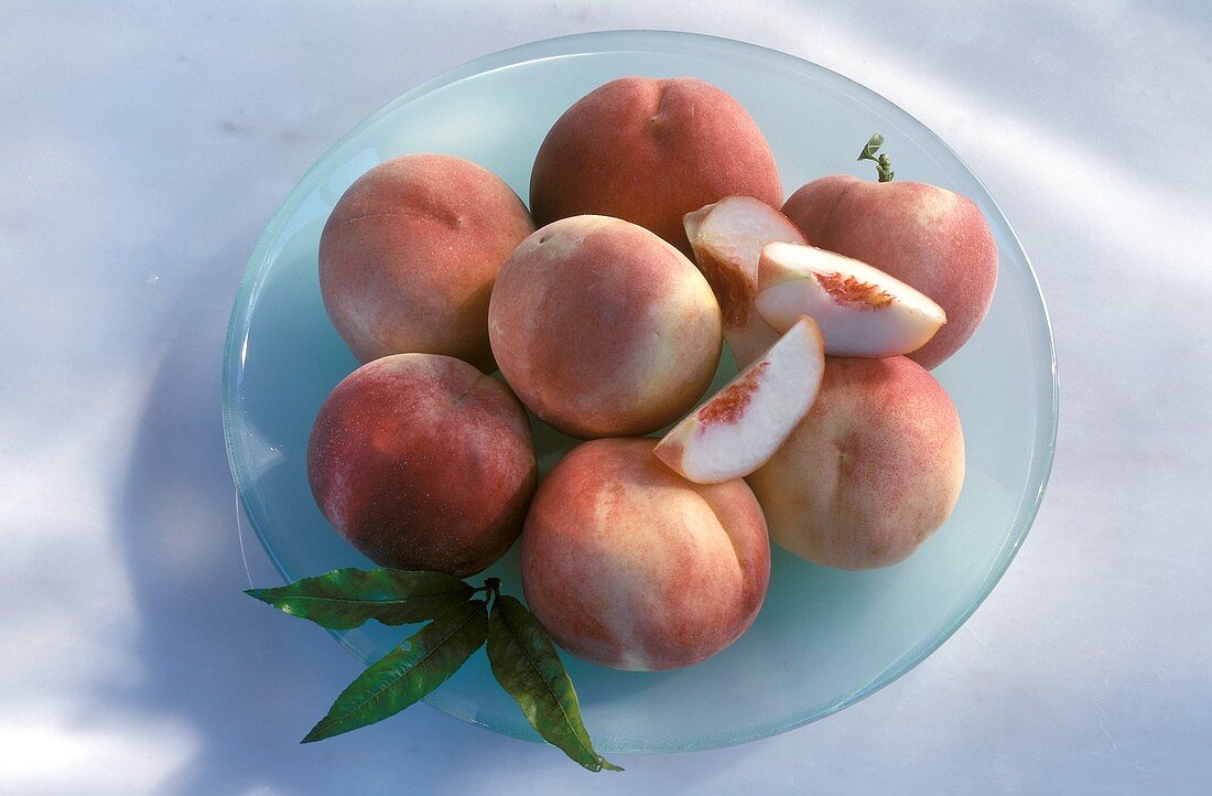 Several peaches and a few peach wedges on plate