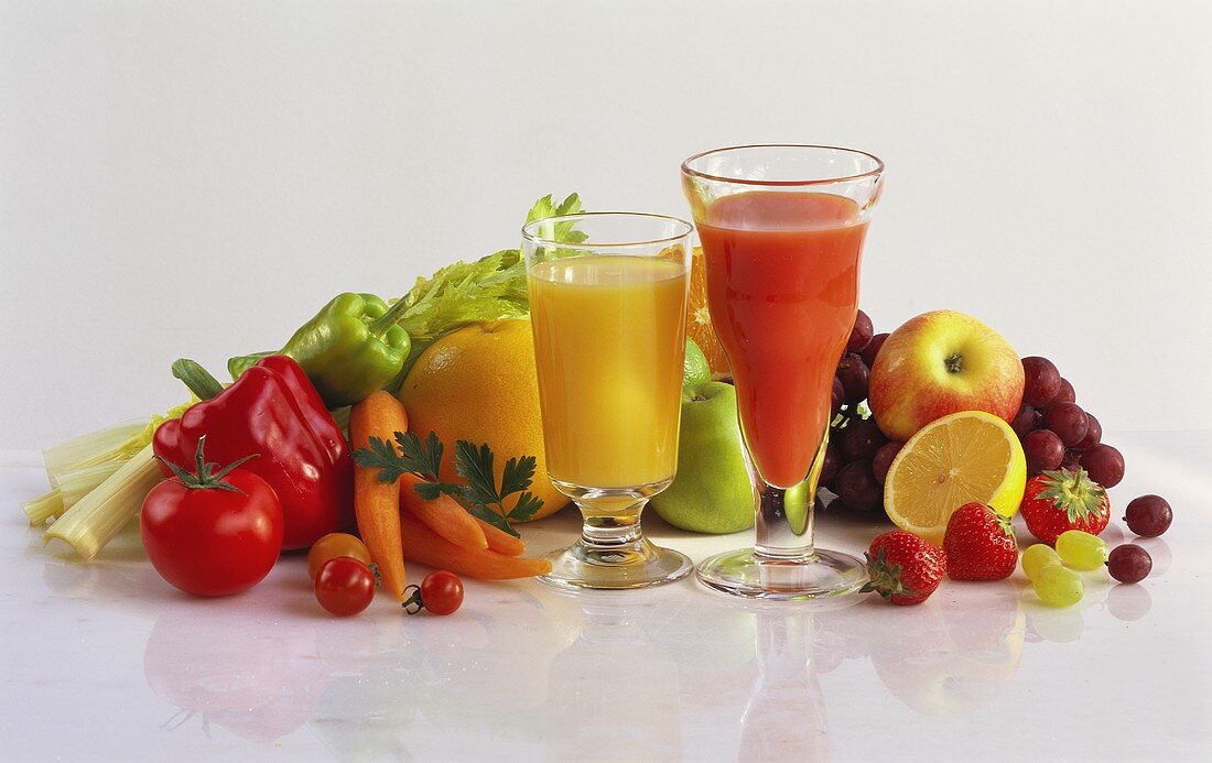 Obstsaft & Gemüsesaft im Glas, daneben frisches Obst & Gemüse