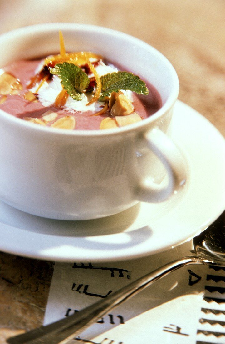 Heidelbeersuppe mit Mandelblättchen, Sahne und Minze in Tasse