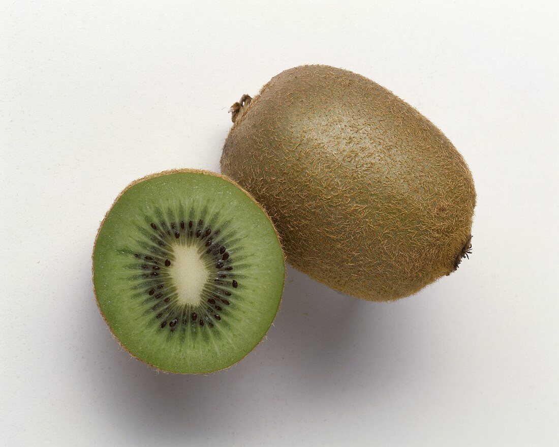 Ganze Kiwi und eine Kiwihälfte auf hellem Untergrund