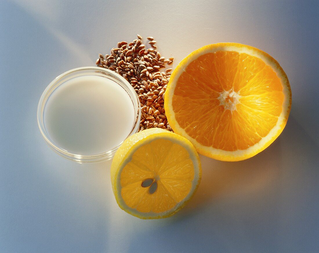 Orangen- und Zitronenhälfte, Leinsamen und Milch im Schälchen