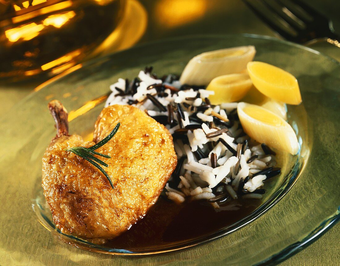 Braised guinea-fowl legs with wild rice and leeks on plate
