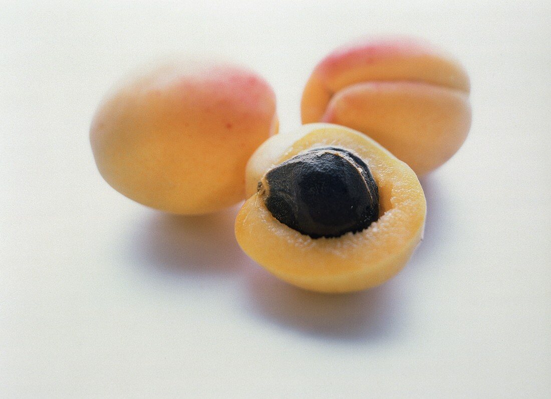 Zwei Aprikosen und Aprikosenhälfte mit Kern