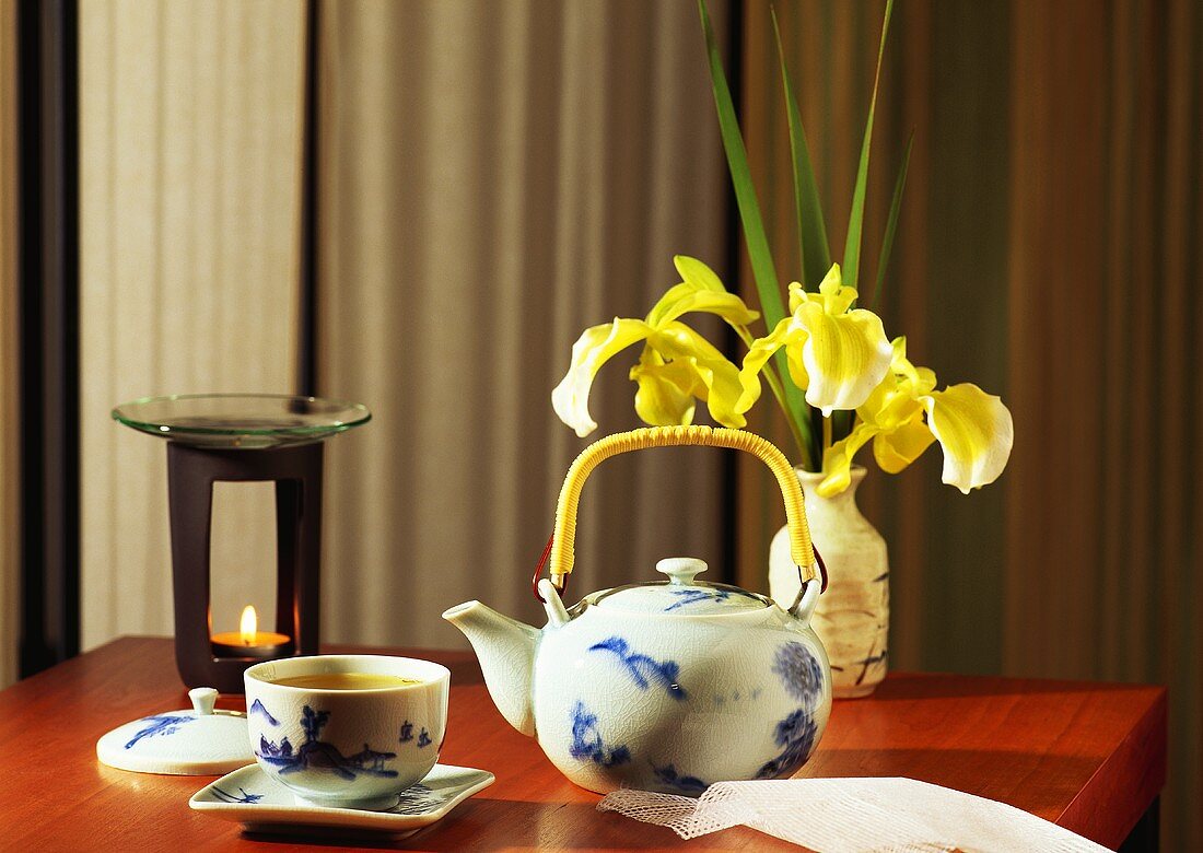Asiatisches Teearrangement mit Duftlampe und Blumen auf Tisch