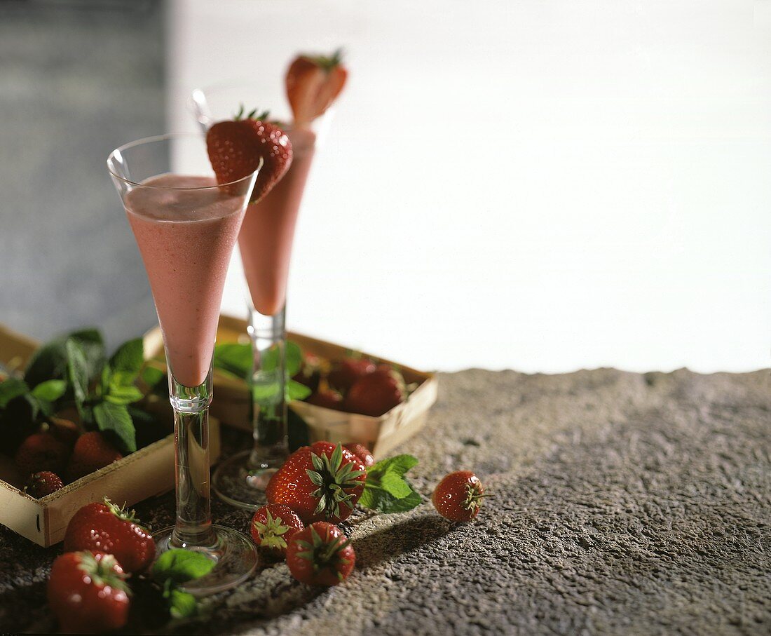 Erdbeer-Prosecco in Gläsern, umgeben von frischen Erdbeeren