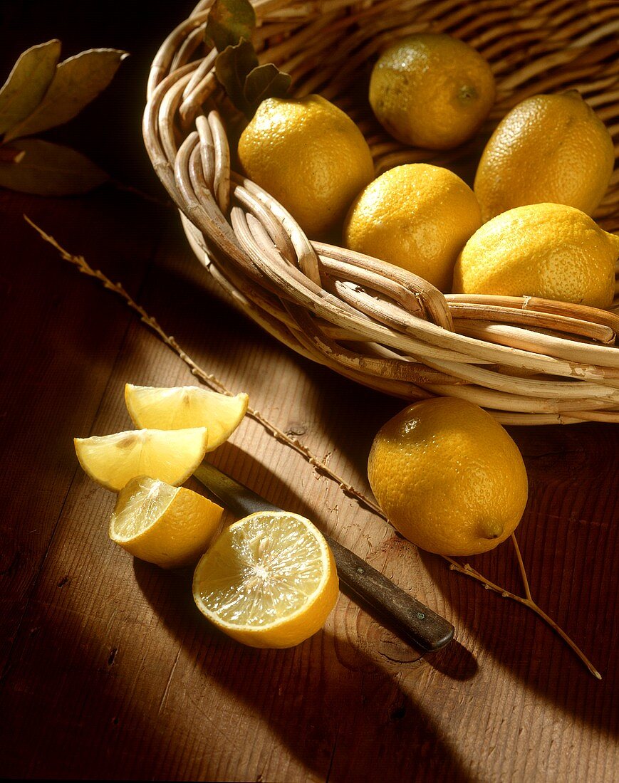 Lemons in a Basket with Sliced Lemons on Wood