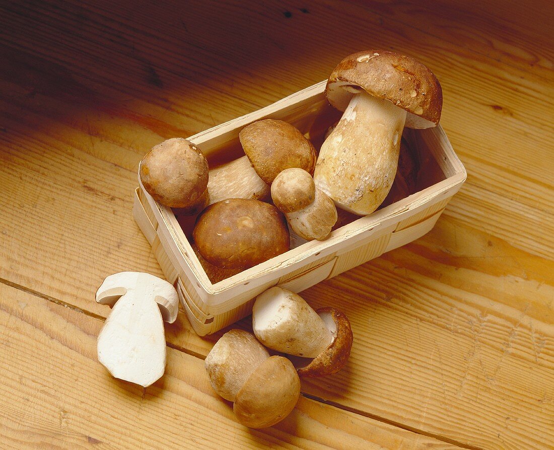 Ceps in and beside chip basket on wooden background