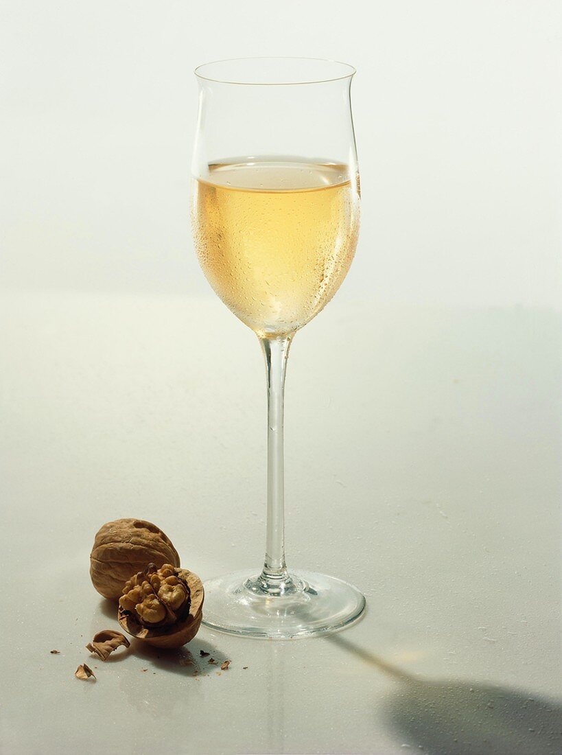 Ein Glas Weißwein mit einer geknackten Walnuss