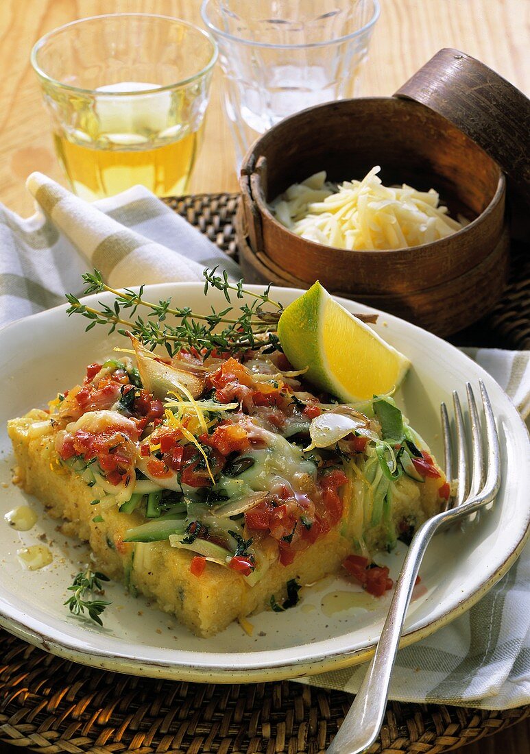 Polenta cake with vegetable crust on plate; grated cheese