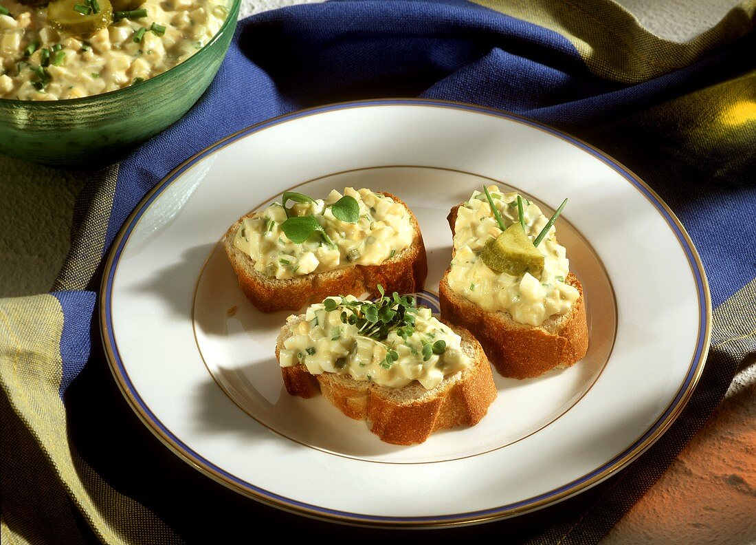 Canapés mit Eieraufstrich und Essiggurken auf Teller