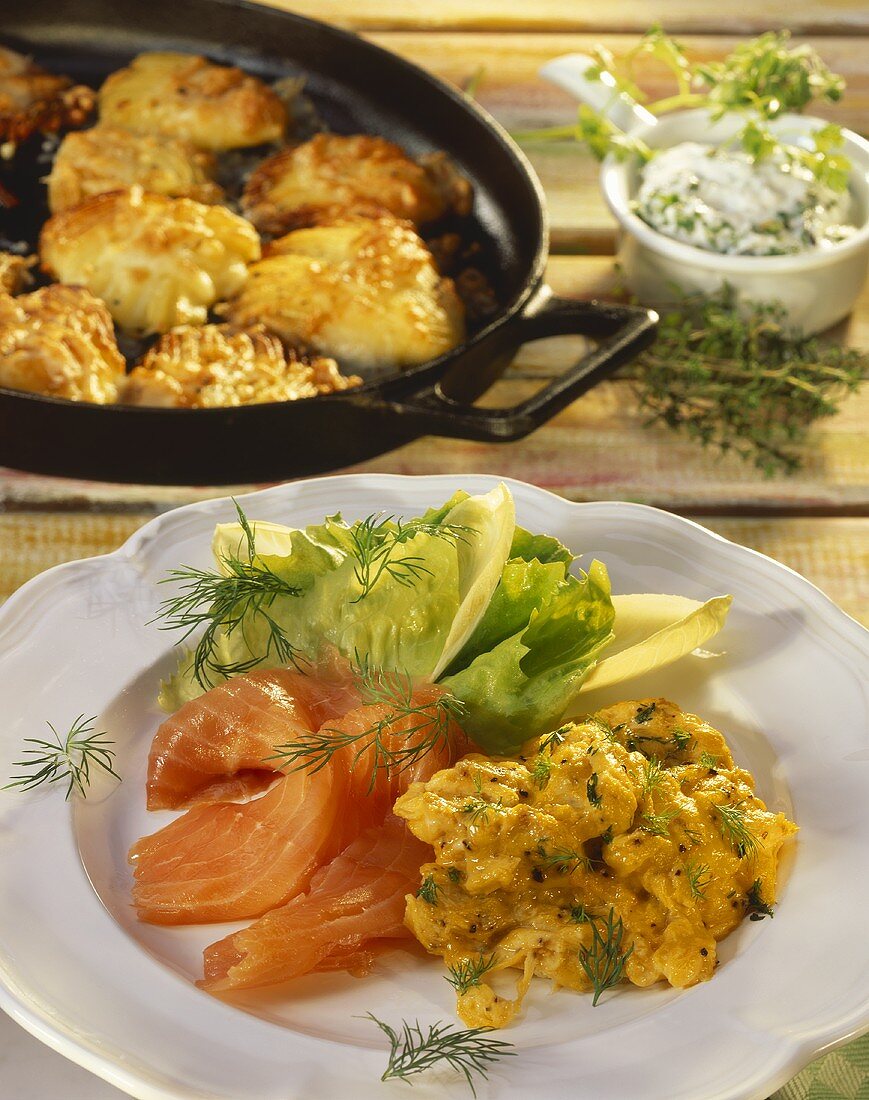 Scrambled egg with salmon on white plate and behind in pan