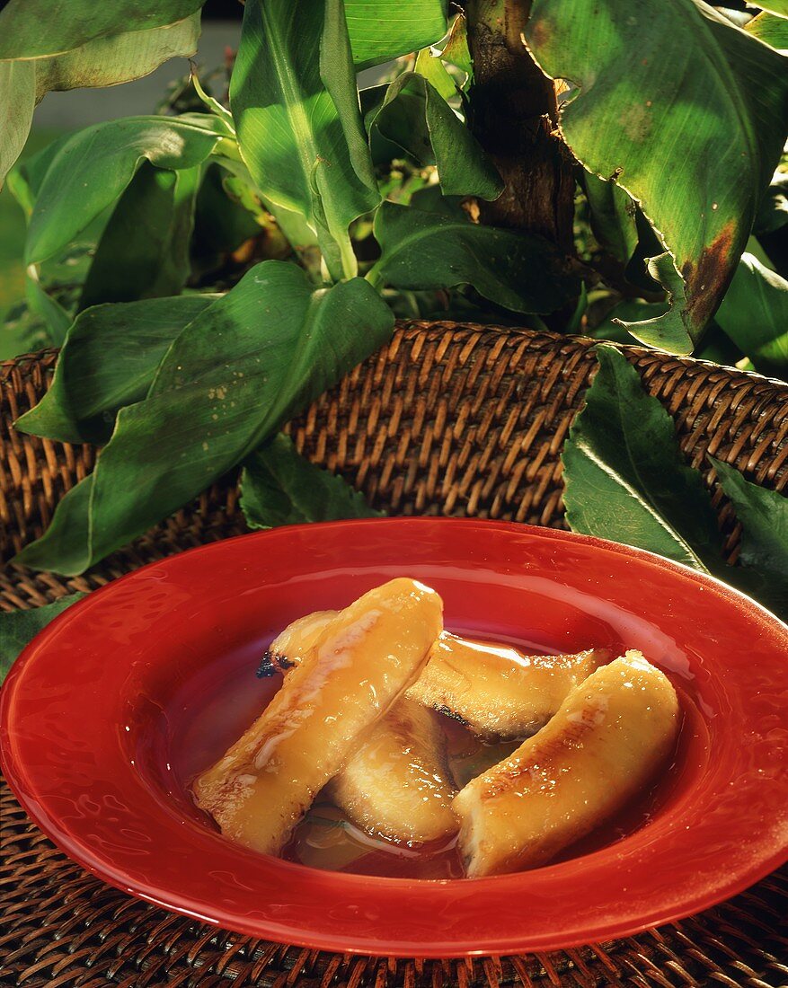 Flambéed bananas in honey sauce on red plate