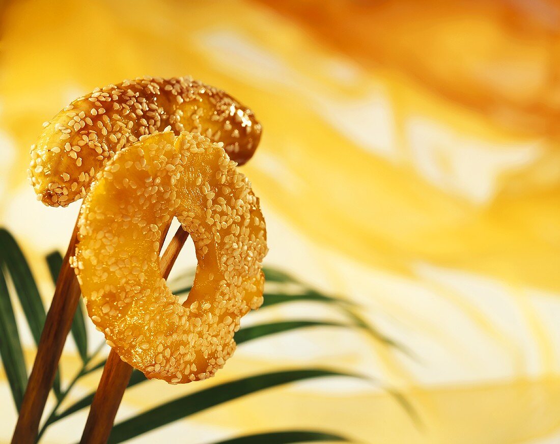 Glazed fruit (pineapple, banana) with sesame on chopsticks