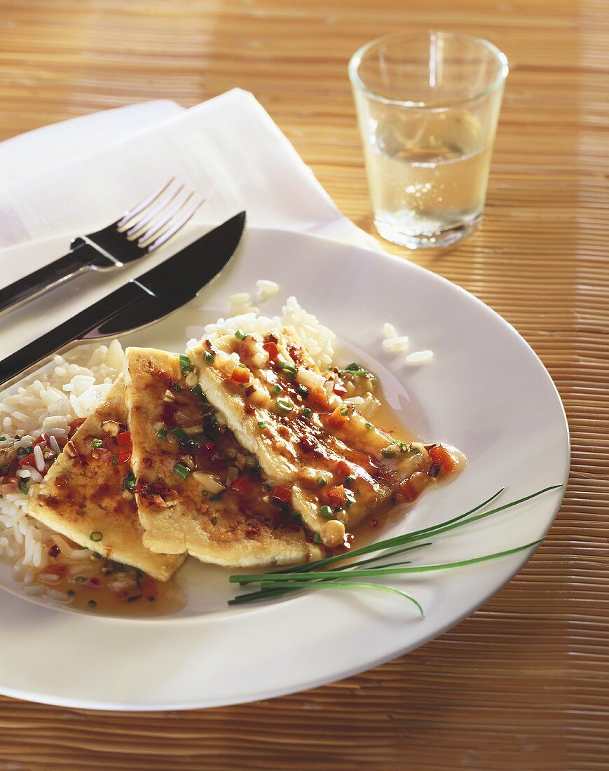 Spicily seasoned tofu escalope with rice on plate with cutlery