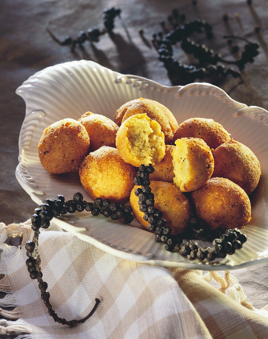 Scharfe Hush Puppies (Maisbällchen) auf Teller; Pfefferkörner