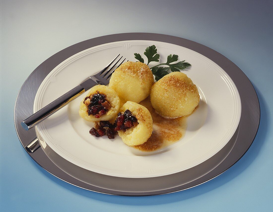 Black pudding dumplings with butter sauce on white plate