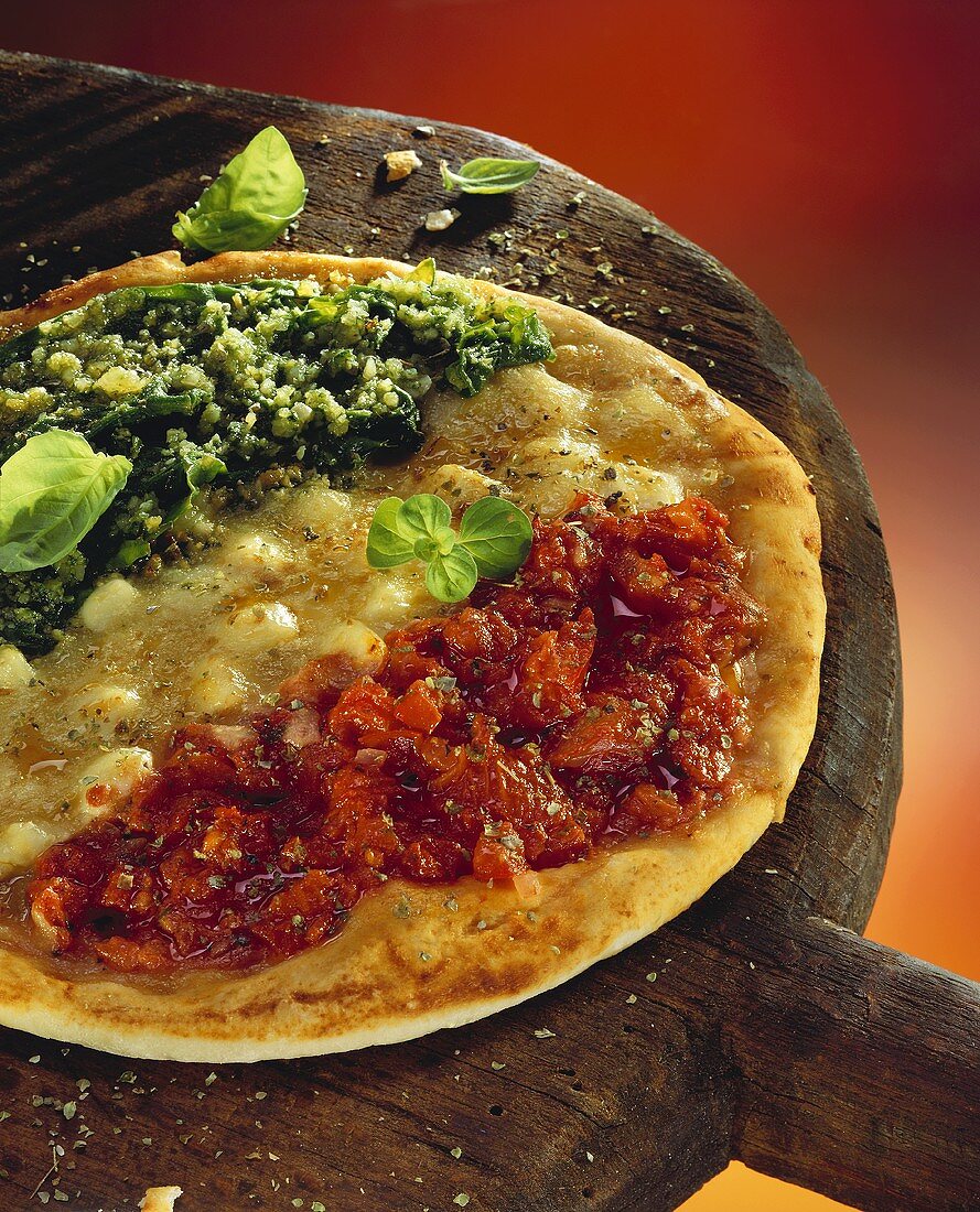 Pizza with tomatoes, spinach & cheese on large wooden paddle