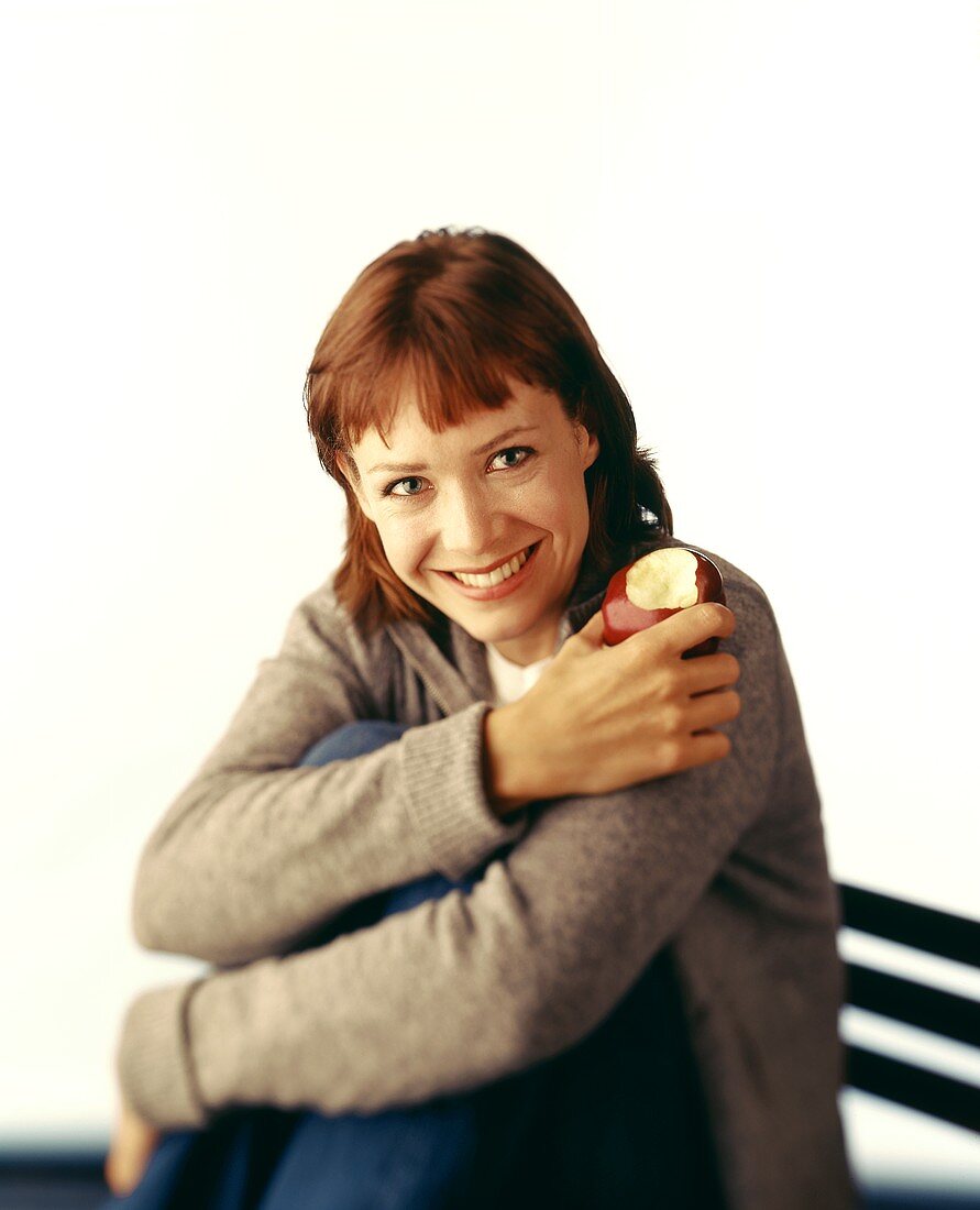 Woman Smiling and Holding a Red Delicious Apple