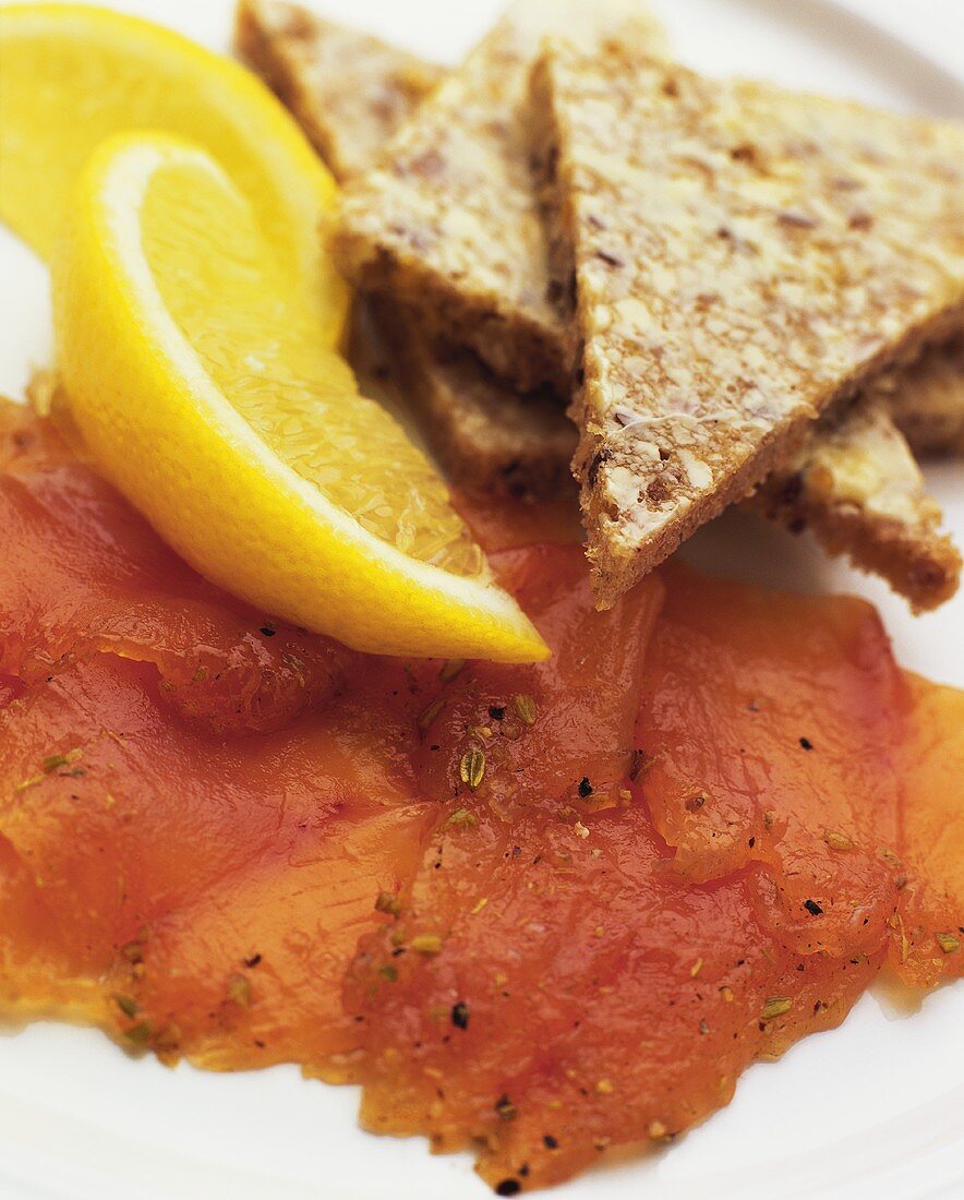 Raw Sliced Salmon with Bread Triangles and Lemon Wedges